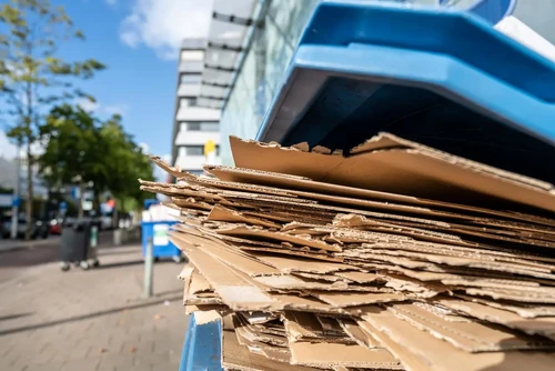 A pile of cardboard boxes recycled in a recycling bin.