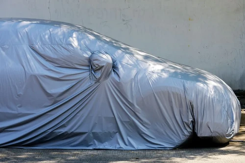 A car sits covered in a durable cover while parked in vehicle storage