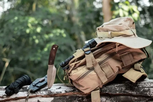 A hunting knife and bag sit on a log during hunting season.