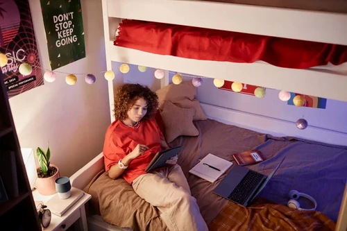 A college student at Missouri State University sits on her bed in her dorm room.