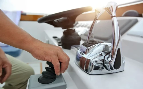A man drives his boat, pushing forward on the throttle to control its engine
