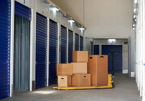 A series of closed storage units, with a pallet of cardboard boxes next to one open unit.
