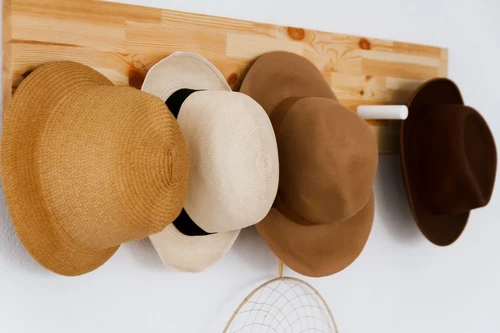 A group of hats hanging on a wooden board.