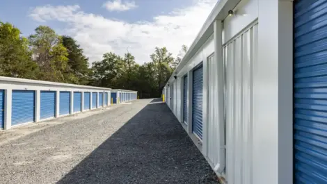 Row of outdoor storage units with metal doors and clear sky above.