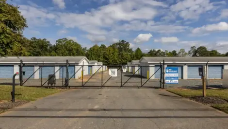 View of the storage facility from outside the fence, showing units and driveway.